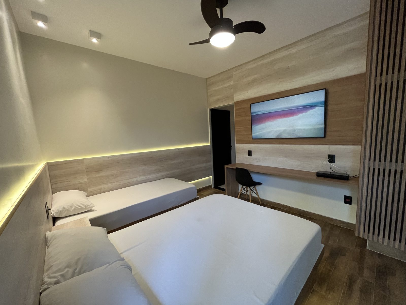 Suíte Real com cama de casal e cama de solteiro, TV, bancada de trabalho e iluminação indireta no Hotel Holambra